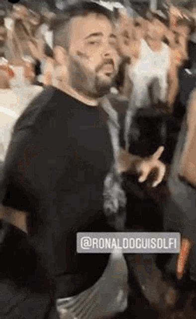 a man with a beard is standing in front of a crowd of people .