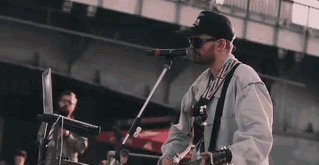 a man is singing into a microphone while playing a guitar and a keyboard .