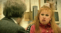 a man and a woman are talking to each other in a room . the woman is making a funny face .