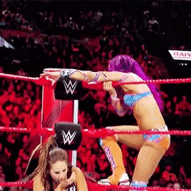 two women are wrestling in a ring with a sign that says raw in the background