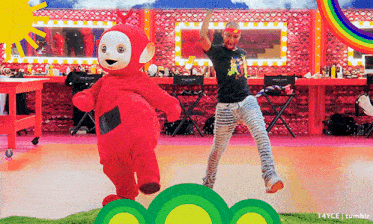 a person in a teletubbies costume is dancing with a man in a black shirt