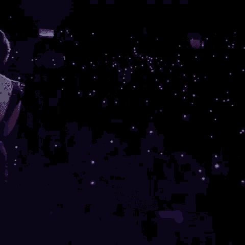 a woman is singing into a microphone on a stage in the dark .