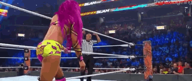a woman with pink hair is standing in a wrestling ring while a referee watches .