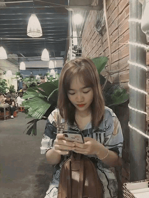 a woman is looking at her phone while sitting in a restaurant