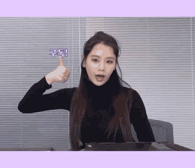 a woman in a black turtleneck is giving a thumbs up in front of blinds