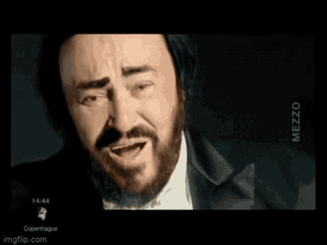 a man with a beard and mustache is smiling and wearing a tuxedo