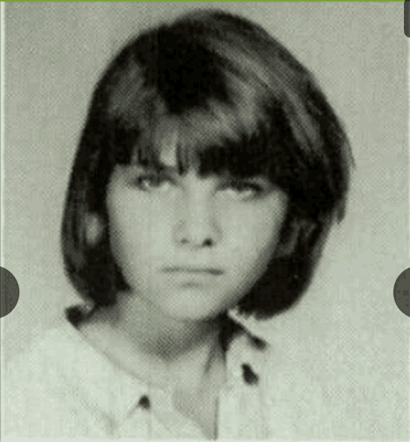 a black and white photo of a young woman with short hair and bangs .