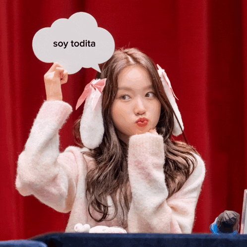a girl wearing bunny ears is holding a sign that says soy todita
