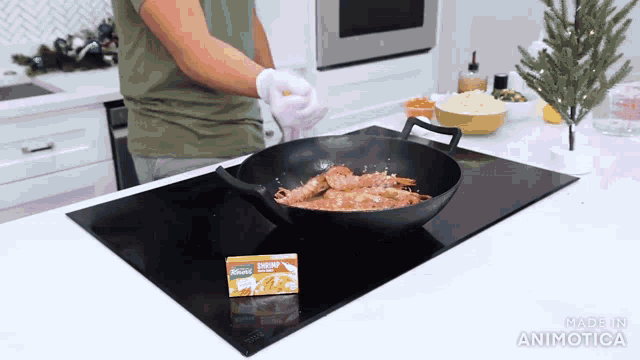 a person is cooking shrimp in a frying pan on a stove top ..