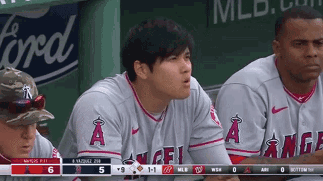 a group of baseball players sitting in a dugout with a ford advertisement in the background