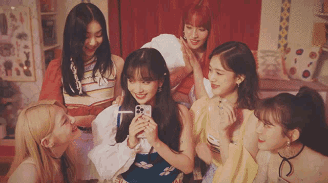 a group of girls are posing for a picture with one girl holding a phone