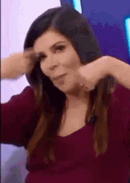 a woman in a red shirt is making a funny face and holding her hair .