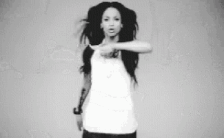 a black and white photo of a woman with dreadlocks pointing at the camera