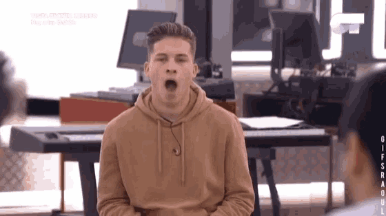 a young man in a brown hoodie is yawning