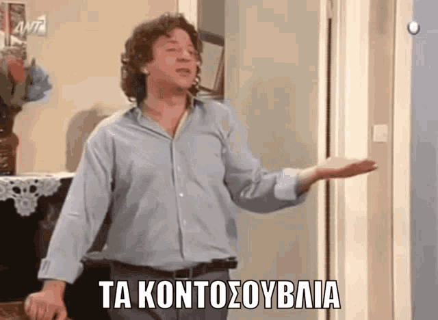 a man in a blue shirt is standing in front of a door with the words ta kontosoubalia written above him