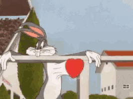 bugs bunny is leaning over a railing holding a heart .