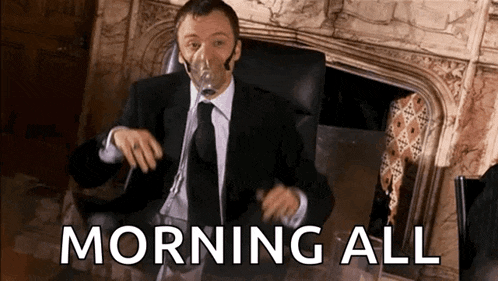 a man wearing an oxygen mask is sitting in front of a fireplace with the words morning all below him .