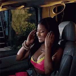 a woman in a pink top is sitting in the back seat of a car talking on a cell phone .