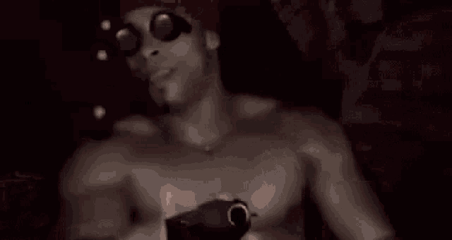 a shirtless man wearing sunglasses and a red hat is holding a flashlight .