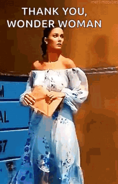 a woman in a blue and white dress is holding a piece of paper and saying thank you , wonder woman .