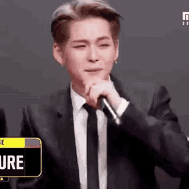 a man in a suit and tie is holding a microphone and talking into it .