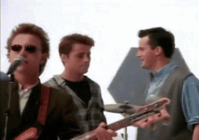 a man singing into a microphone while another man holds a guitar
