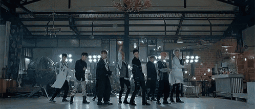 a group of men are standing in a row on a dance floor in a room .