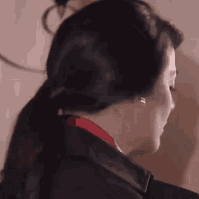 a close up of a woman wearing a black jacket and earrings .