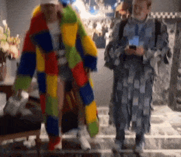 a man in a colorful coat is standing next to a man in a gray coat .