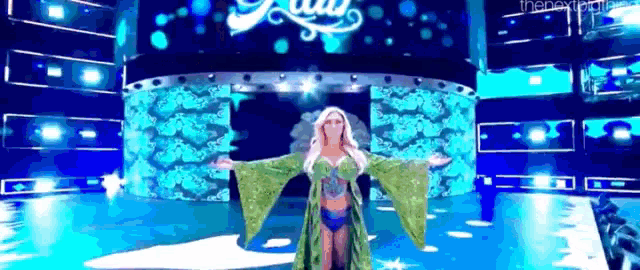 a woman is standing on a stage with her arms outstretched in front of a large screen .