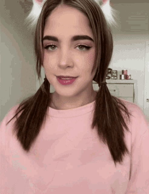 a woman wearing pigtails and cat ears is smiling
