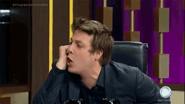 a man in a suit is sitting in a chair eating a piece of food .