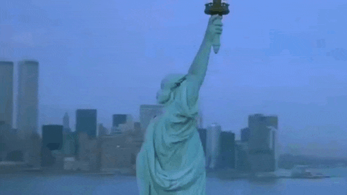 the statue of liberty is holding a torch in front of a city skyline