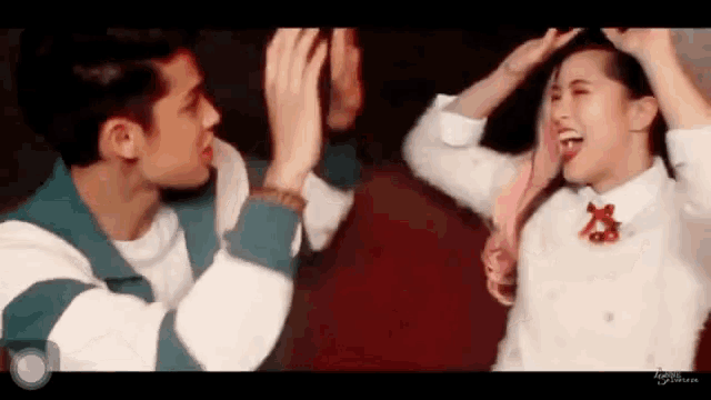 a man and a woman are giving each other a high five while standing next to each other .