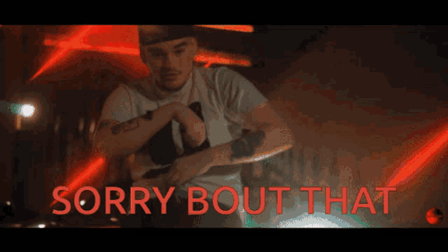 a man with a tattoo on his arm is standing in front of a sign that says sorry bout that