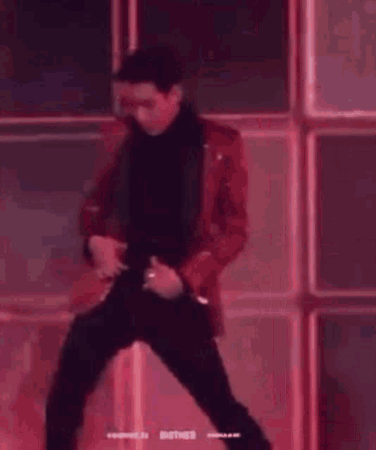 a man in a red suit and black pants is dancing on a stage .