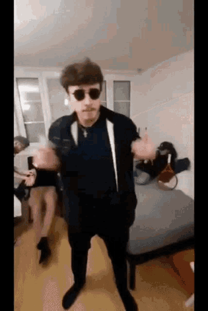a man wearing sunglasses and a mustache is dancing in a room .