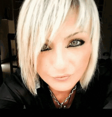 a close up of a woman 's face with blonde hair and a necklace