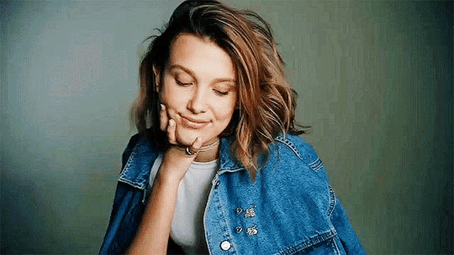 a woman is wearing a denim jacket and a white shirt .