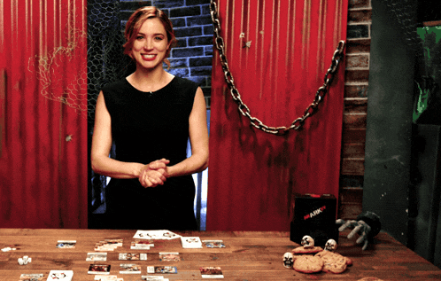 a woman in a black dress stands in front of a red wall with a box that says ' ambush ' on it