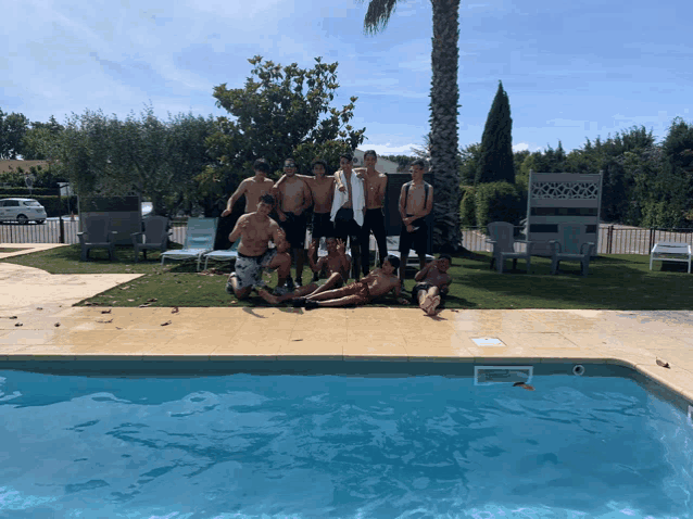 a group of men are posing for a picture next to a pool