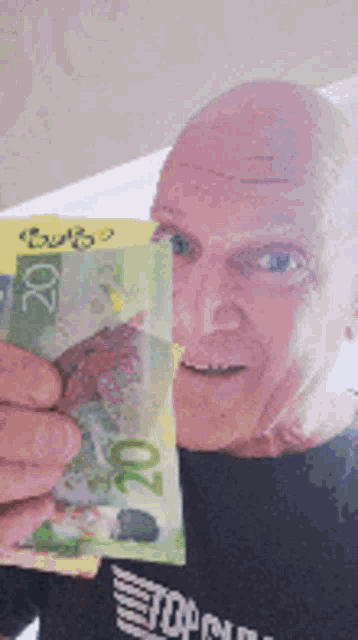 a bald man is holding a 20 dollar bill