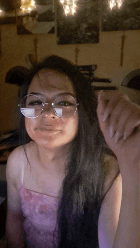 a woman wearing glasses and a pink top is looking at the camera