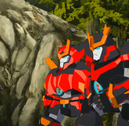 two transformers are standing next to each other in front of a rock wall
