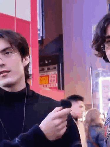 a man wearing glasses holds a cell phone in his hand