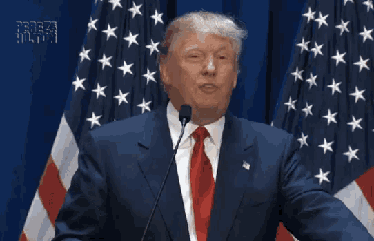 a man in a suit and tie is giving a speech and the word covfefe is on the screen