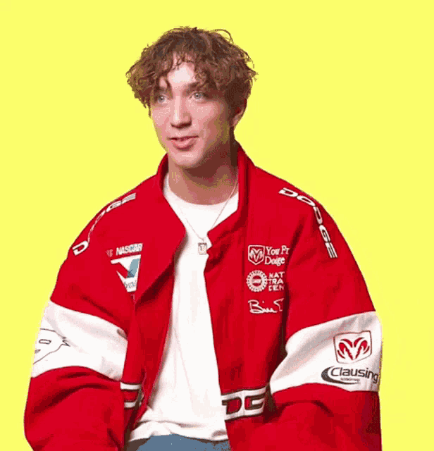 a man wearing a red jacket that says dodge on the front