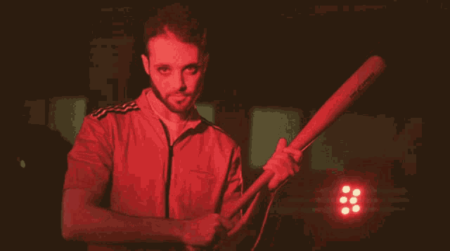 a man in a red shirt is holding a baseball bat that says slazenger on the side