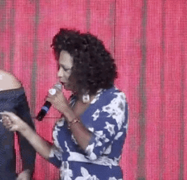 a woman in a blue dress is singing into a microphone on a stage .