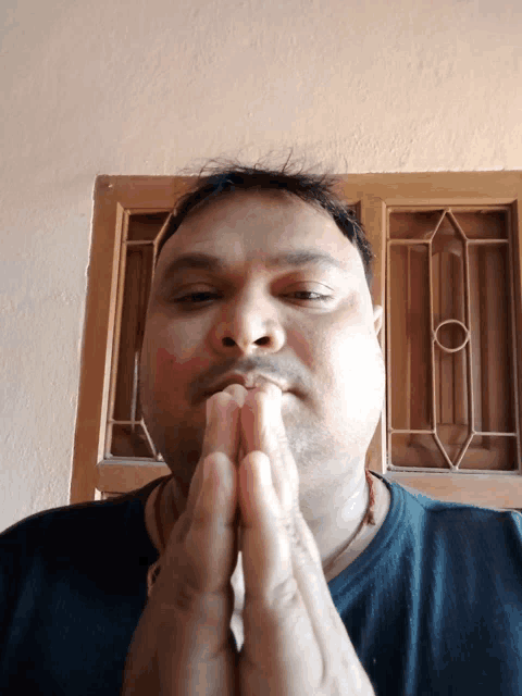 a man with his hands folded in front of his mouth